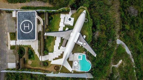 an aerial view of a plane parked in front of a house with a swimming pool