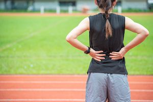 a woman standing on a running track with her back to the camera, looking down