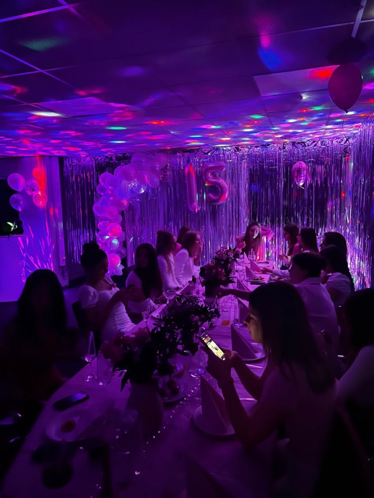 a group of people sitting around a table in a room with balloons and streamers