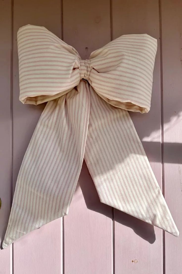 a bow tie hanging on the side of a wooden building with pink paint and white stripes