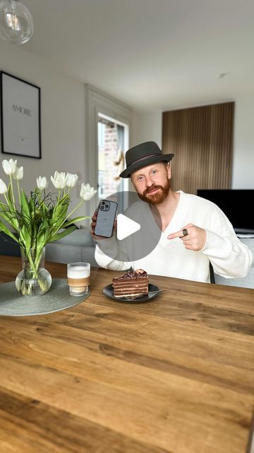 a man sitting at a table with a cell phone in front of him and some flowers