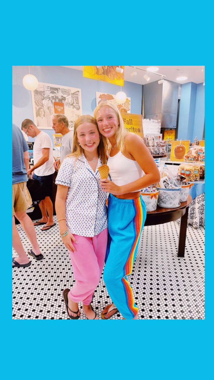 two women standing next to each other in front of a table with food on it