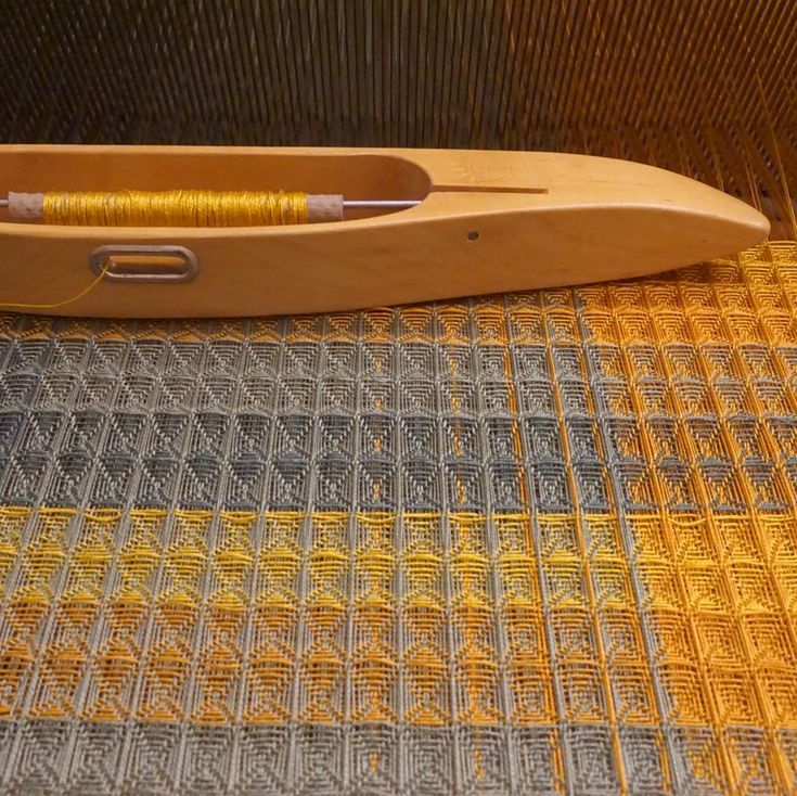 a wooden boat sitting on top of a floor next to a woven material covering the floor