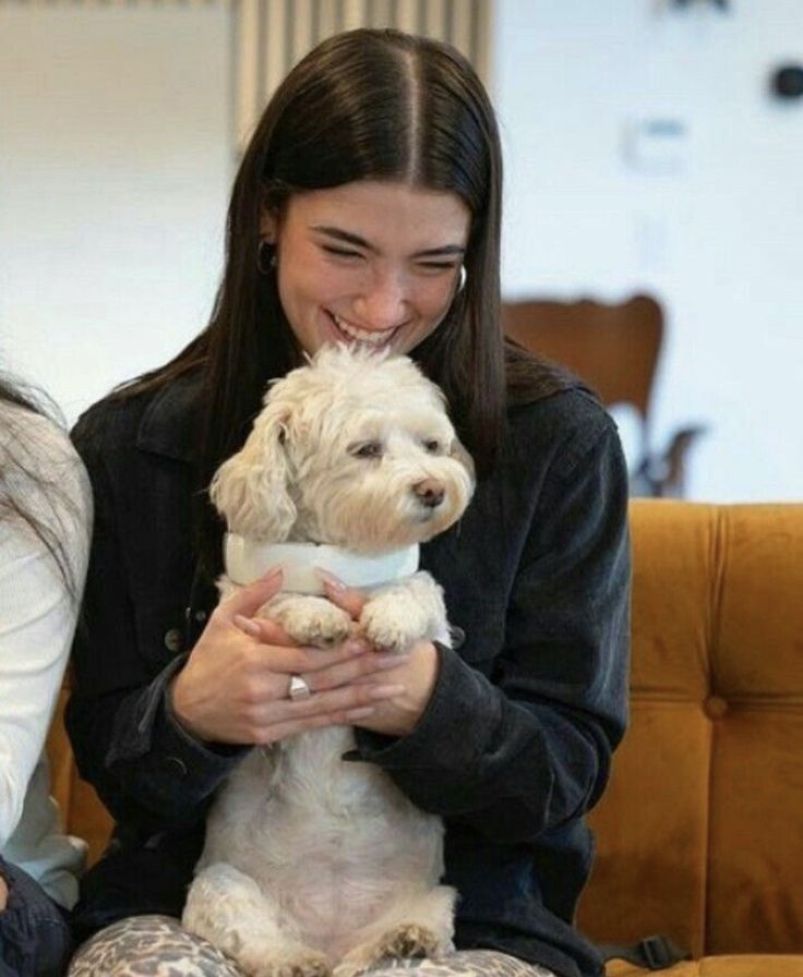 a woman sitting on a couch holding a white dog