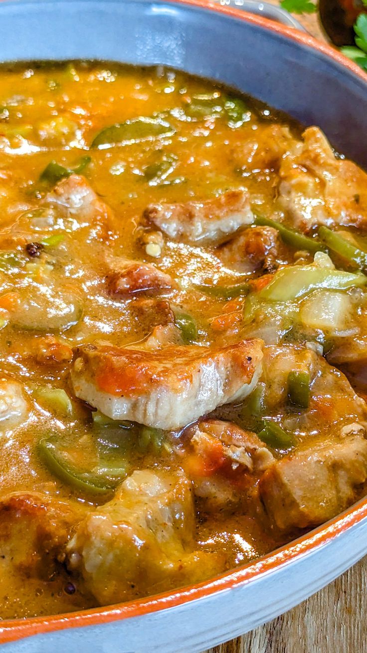 a bowl filled with meat and vegetables on top of a wooden table