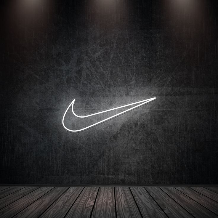 the nike logo is lit up against a dark wall with three spotlights on it