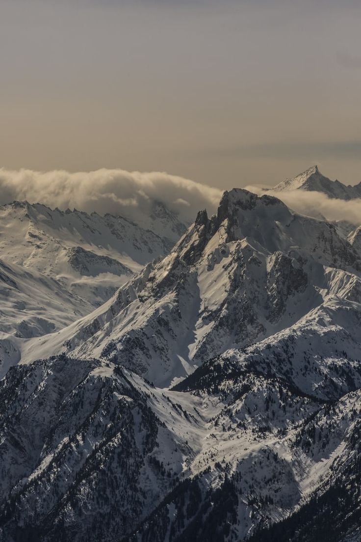 the mountains are covered with snow and clouds in this view from high up on top