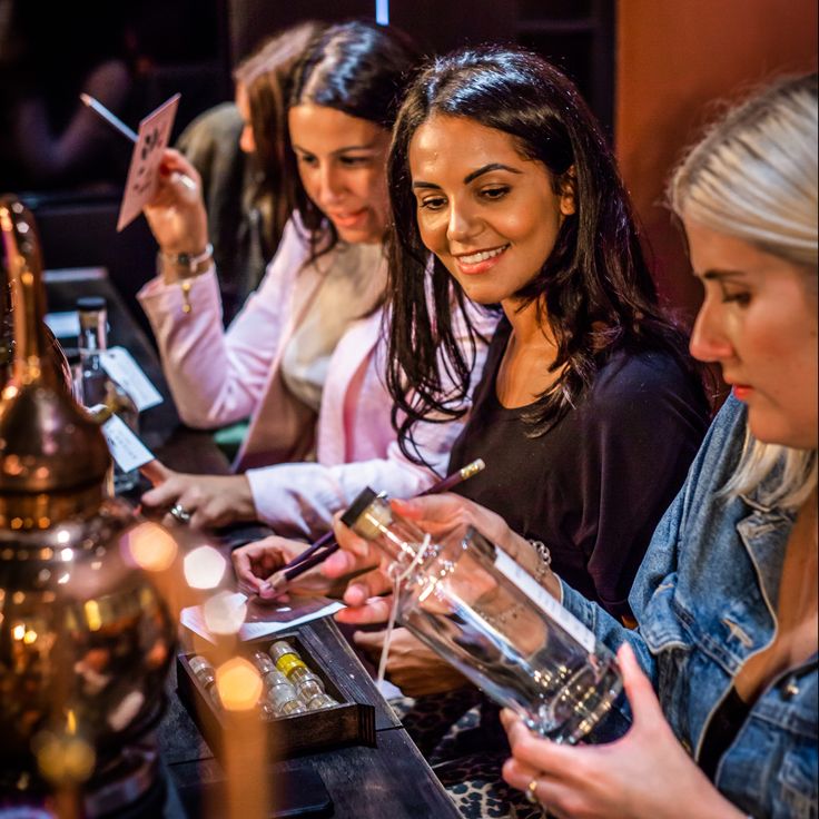 three women are sitting at a bar and one is holding a wine glass in her hand