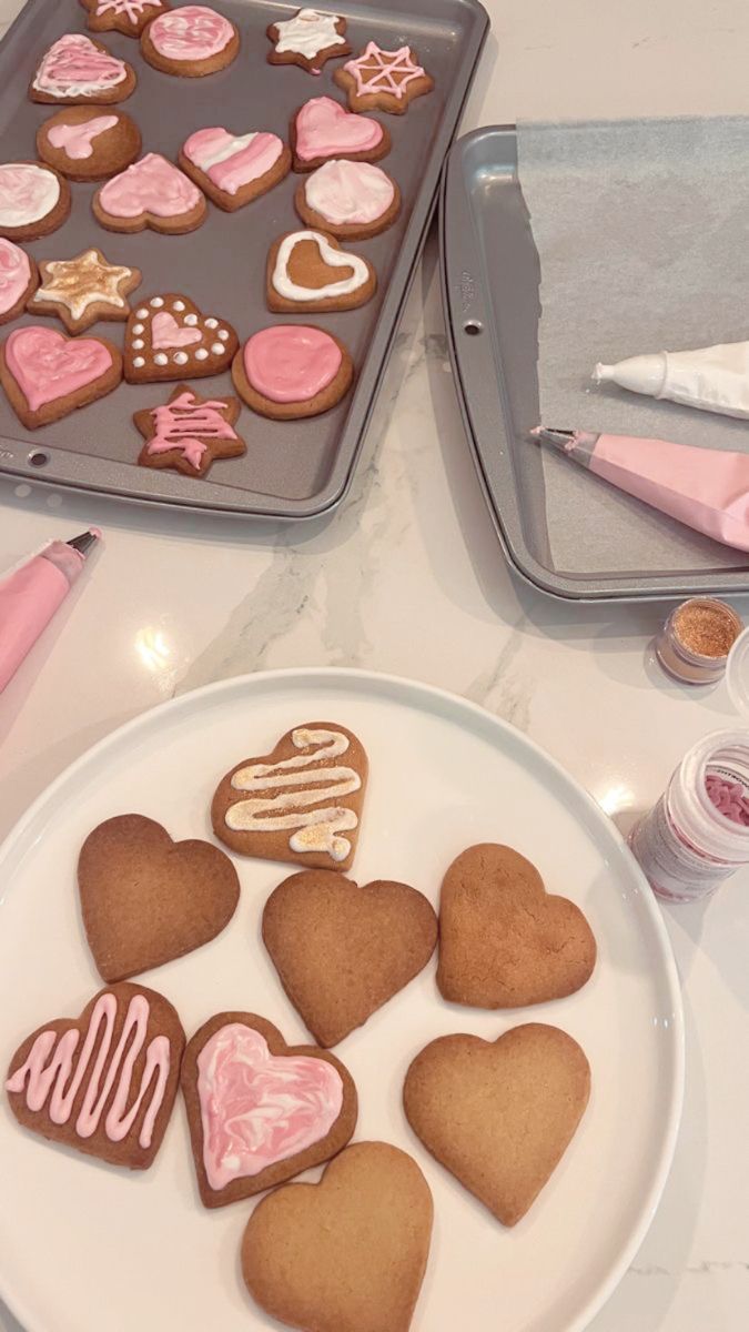 some heart shaped cookies are on a plate next to a cookie tin with pink icing