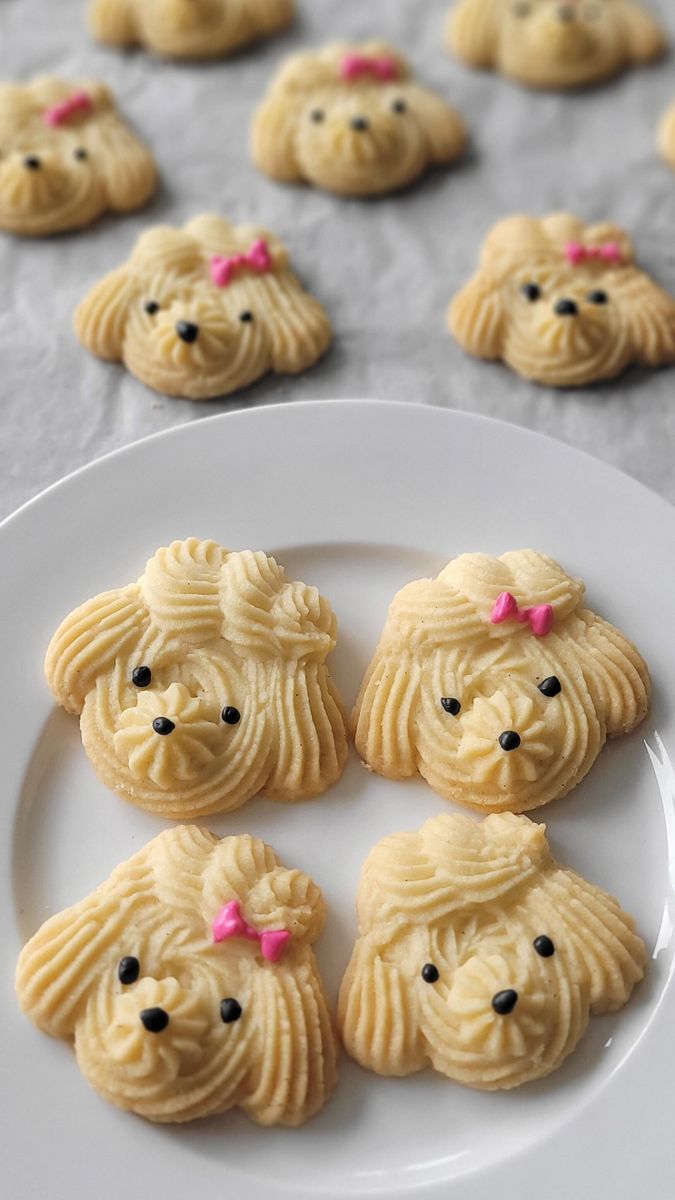 some cookies are on a white plate with black eyes and pink bows in their ears