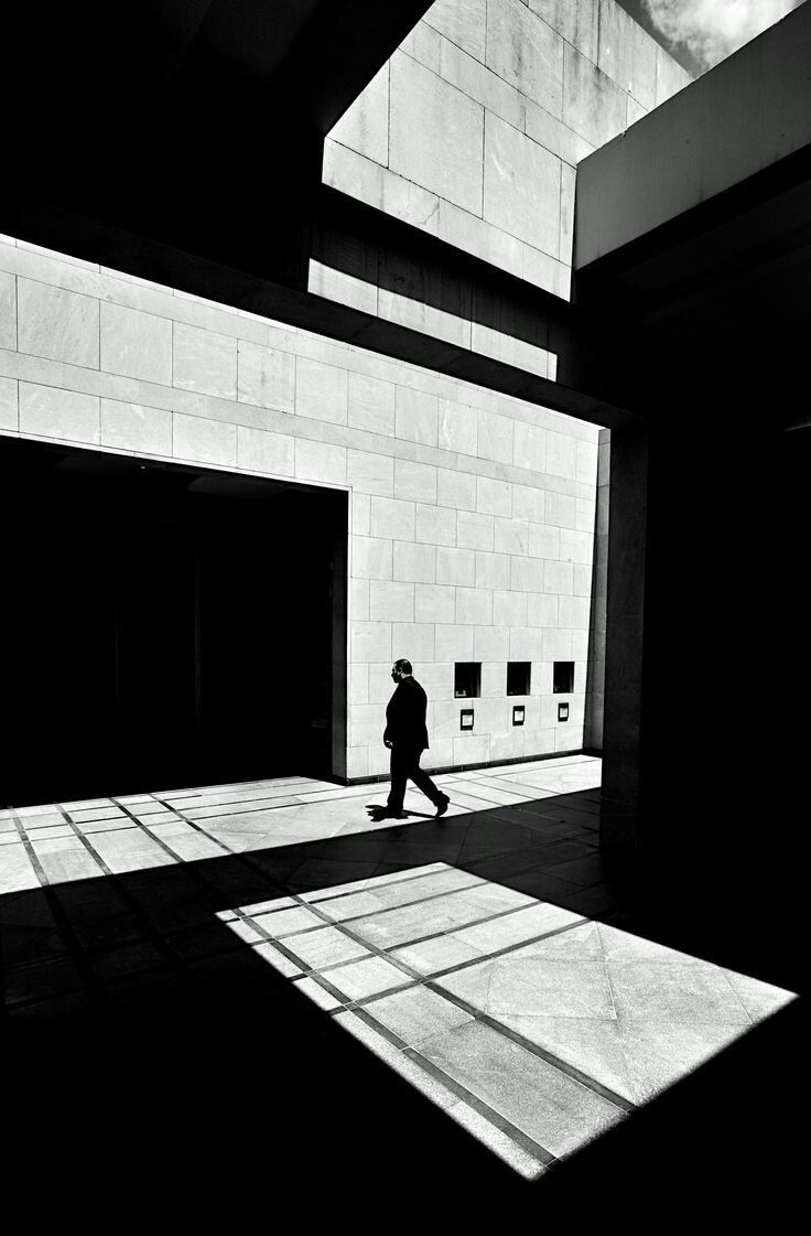 black and white photograph of person walking in an empty room