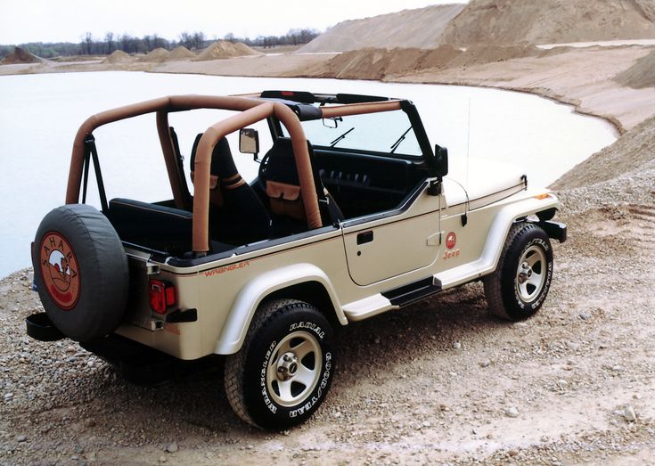 the jeep is parked on the side of the road by the water's edge