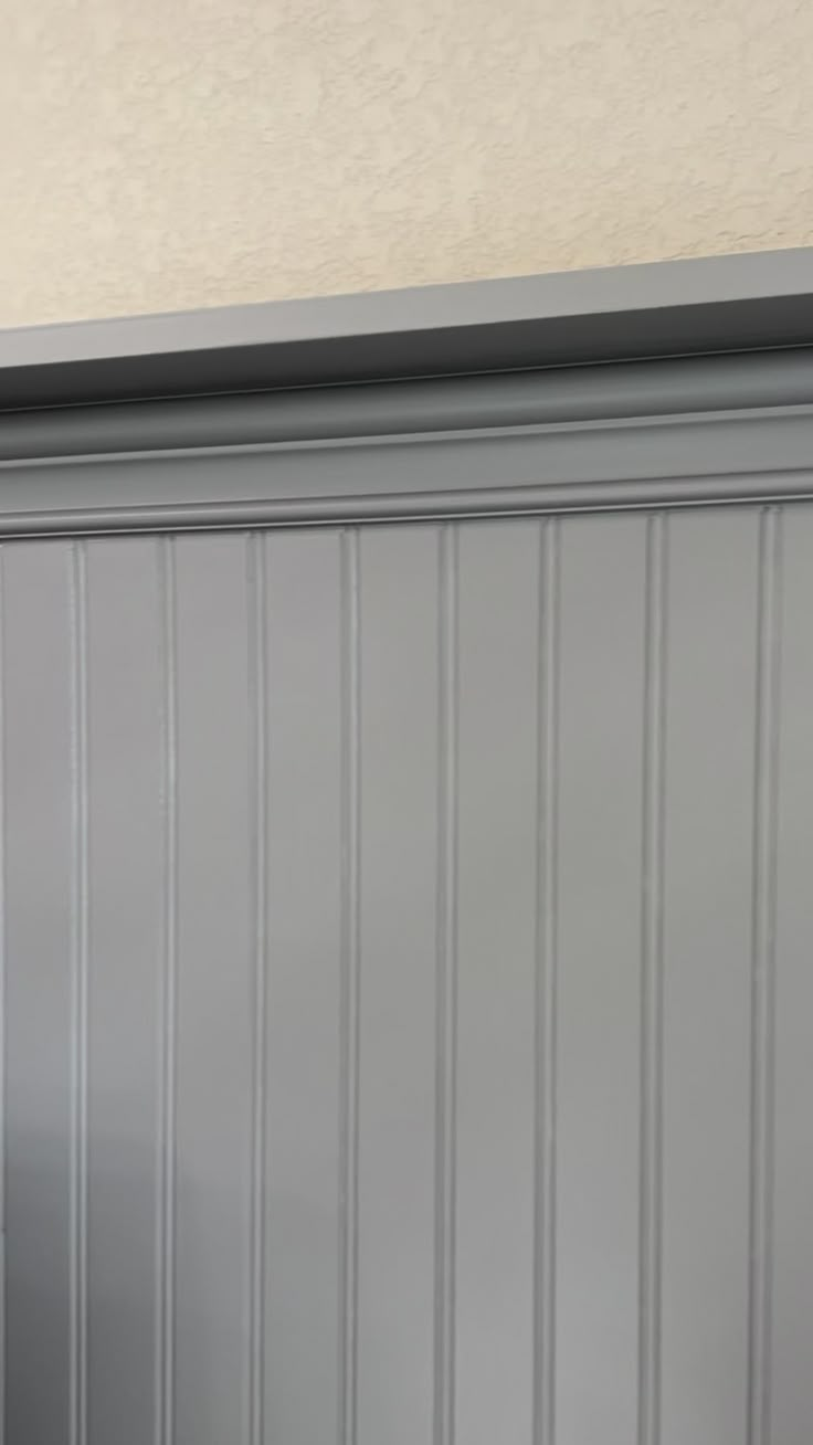 a cat sitting on top of a wooden shelf next to a wall with striped walls