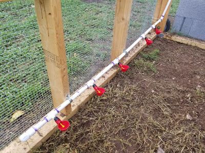 several red and white hoses are attached to the side of a chicken coop fence