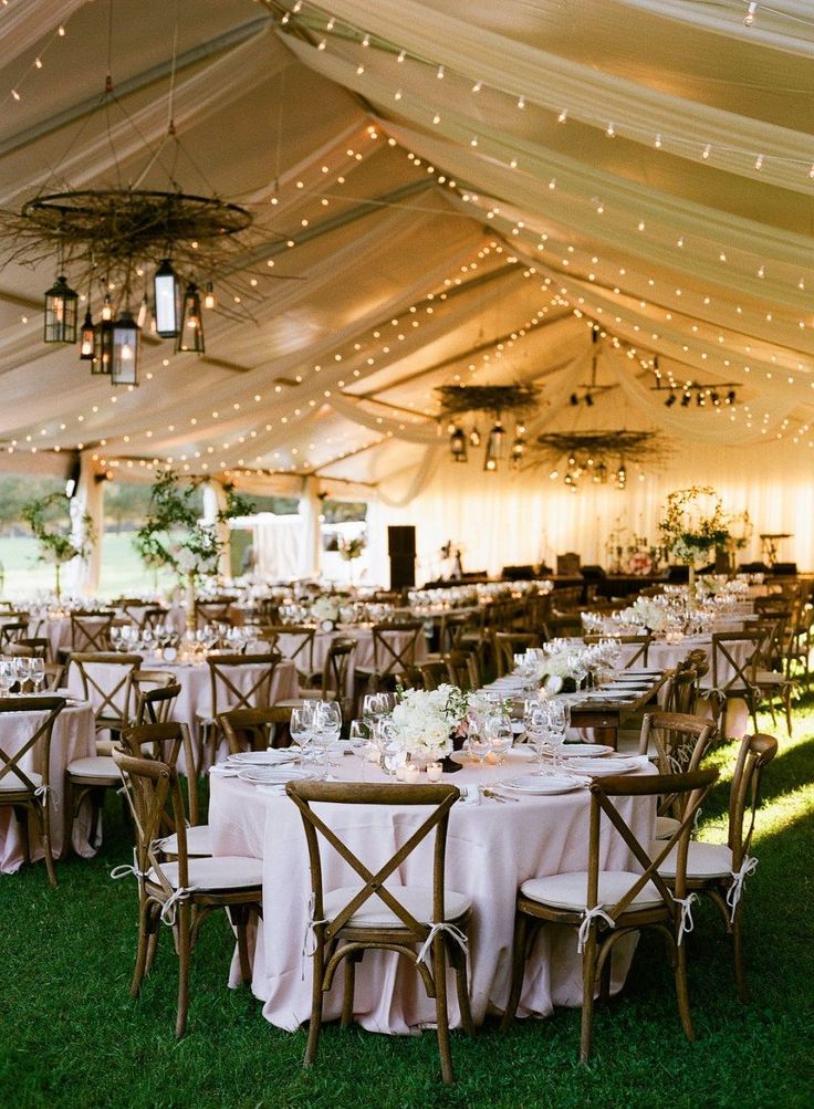 an outdoor tent with tables and chairs set up for a formal dinner or reception in the grass