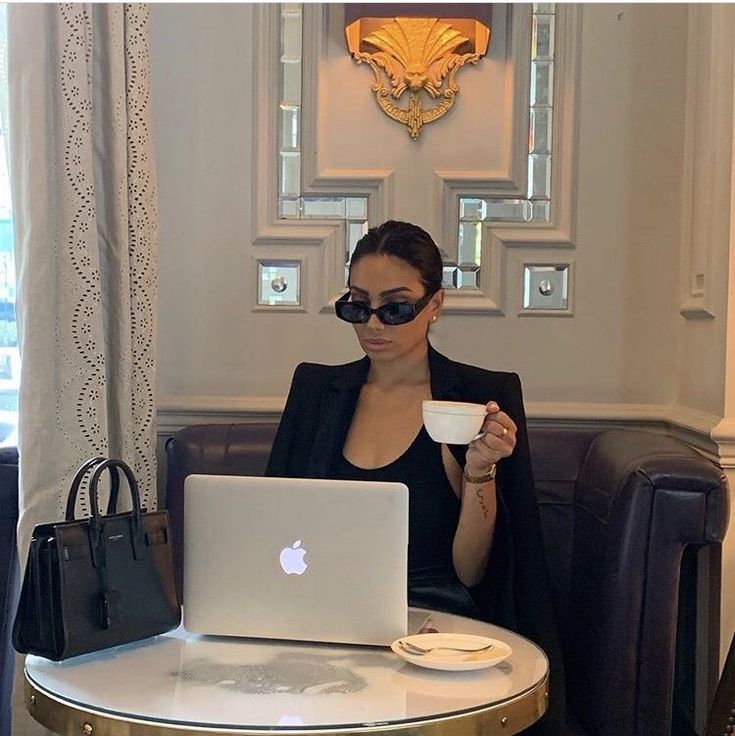 a woman sitting at a table with a laptop and cup in front of her,