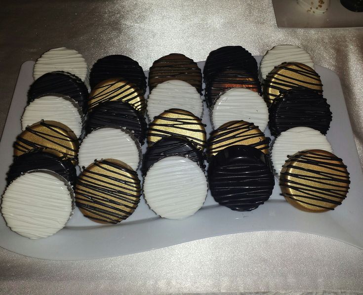 a white plate topped with black and gold desserts on top of a silver table