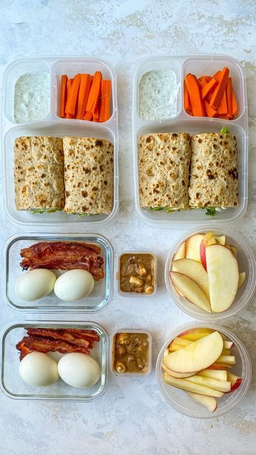 four plastic containers filled with food on top of a white countertop next to carrots, apples, and crackers