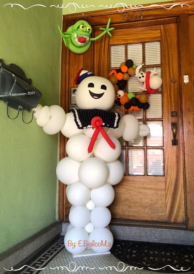 an inflatable snowman is on the front door with balloons attached to it