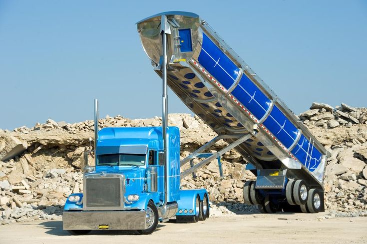 a blue dump truck parked next to a pile of rocks