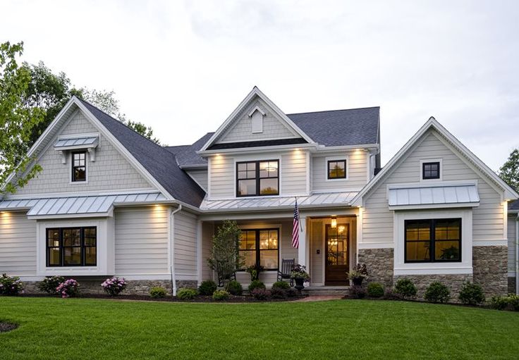 a large white house with lots of windows and lights on it's front porch