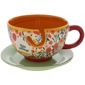 an orange and white flowered tea cup on a saucer with a red handle