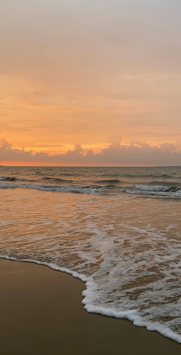 the sun is setting over the ocean with waves coming in