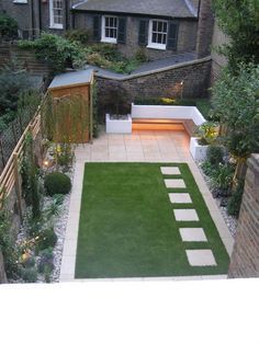 an outdoor garden with grass and steps leading to the back yard, surrounded by brick buildings