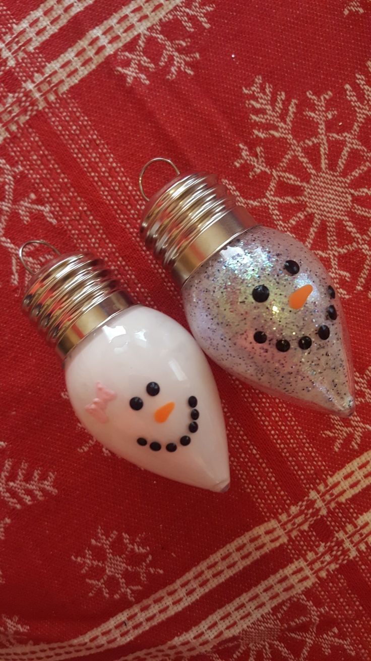 two glass ornaments are sitting on a red cloth with snowflakes in the background