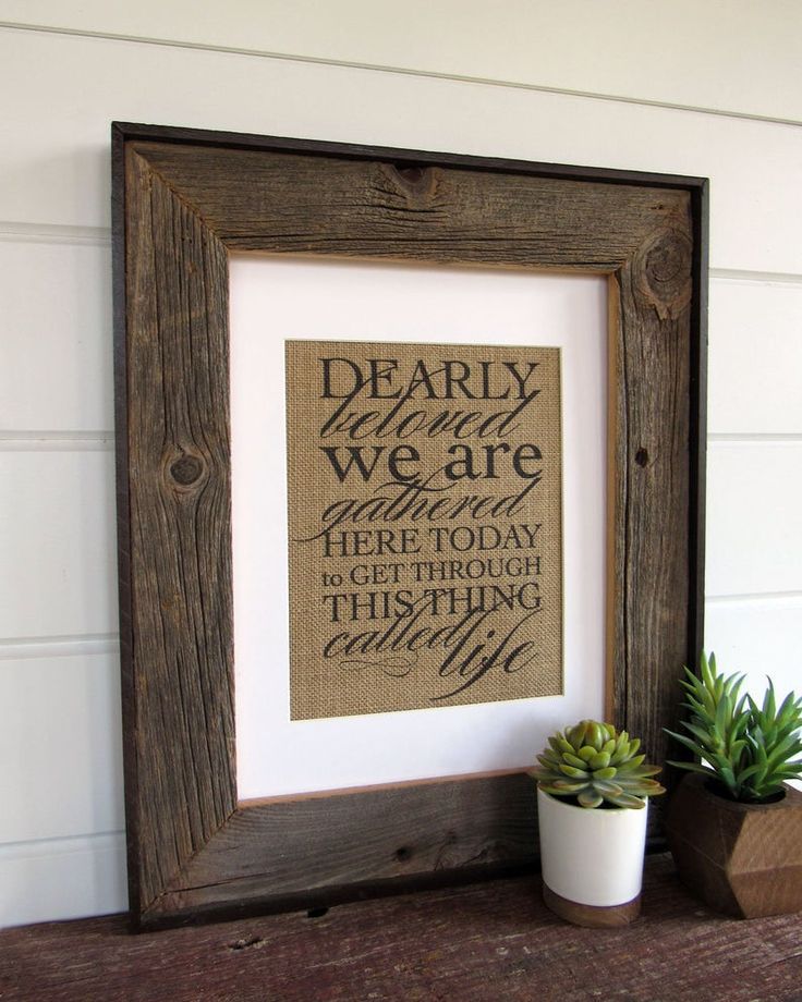 a small potted plant sitting on top of a wooden shelf next to a framed print