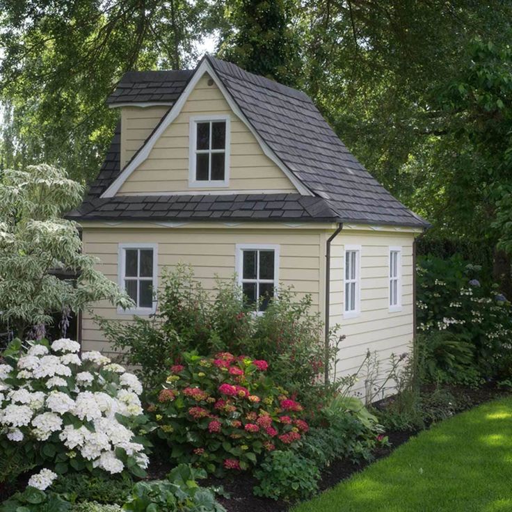 a small house surrounded by flowers and trees