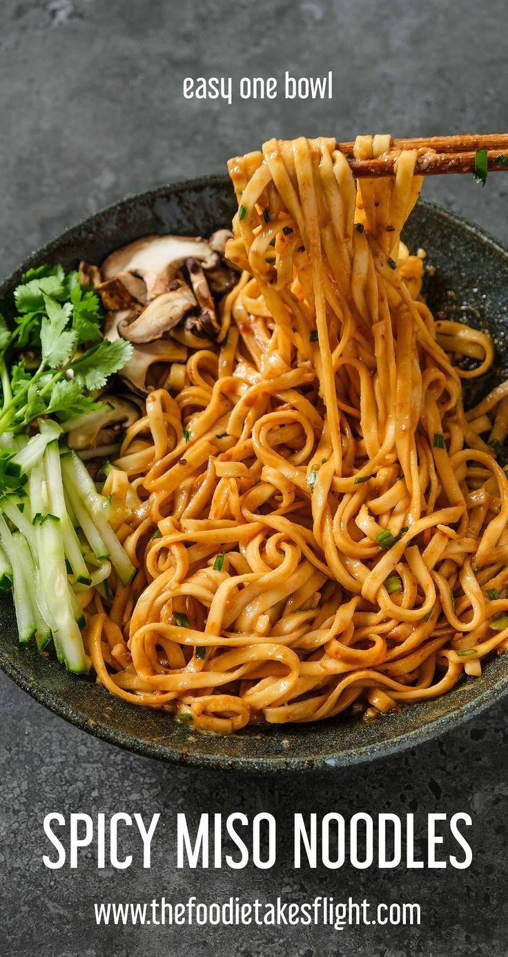 a bowl filled with noodles and vegetables next to chopsticks on top of it