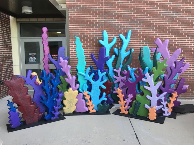 several colorful corals are on display in front of a building with a brick wall