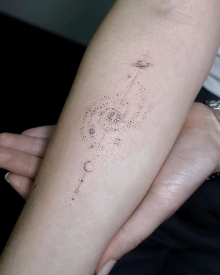 a woman's arm with a tattoo on it that has an image of the sun and stars