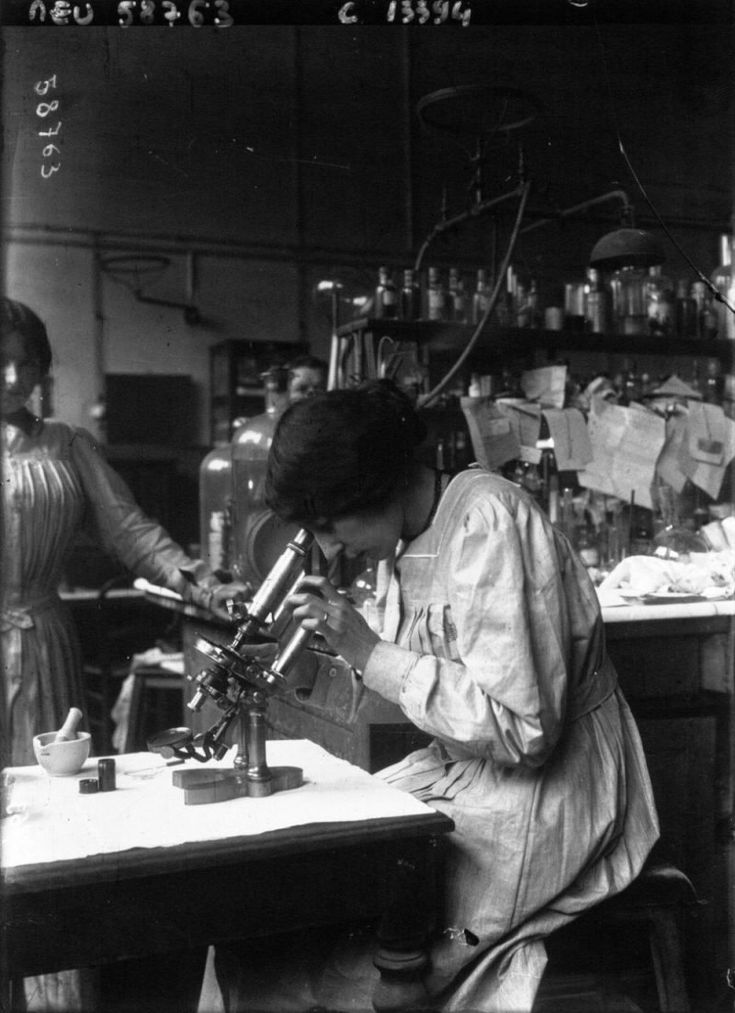 an old black and white photo of two women working in a lab with microscopes