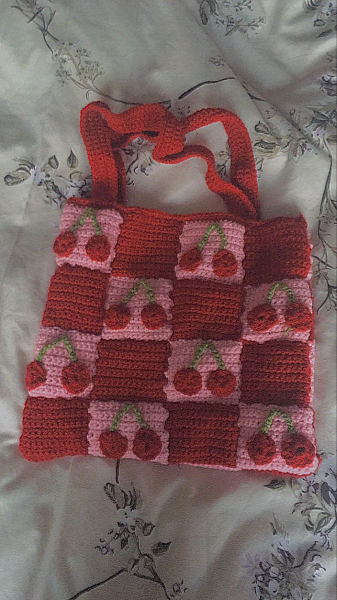 a red crocheted purse sitting on top of a bed