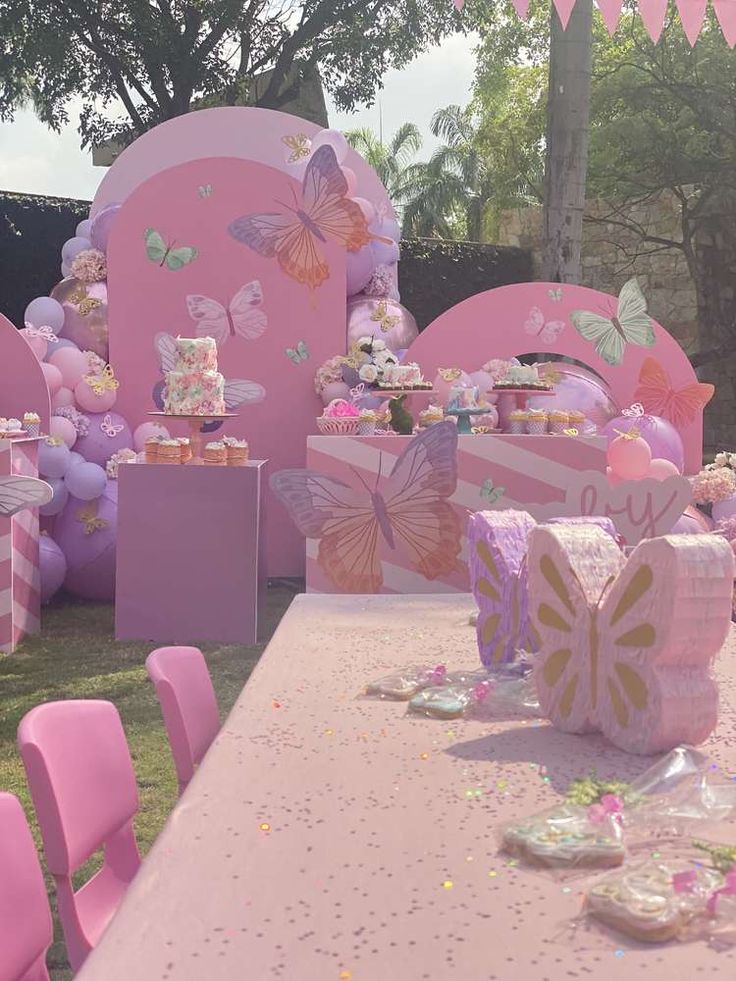 a table with pink and purple decorations on it at a birthday party or baby shower