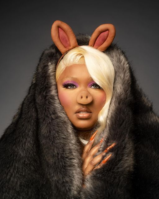 a woman with bunny ears and makeup is wearing a fur coat over her head,