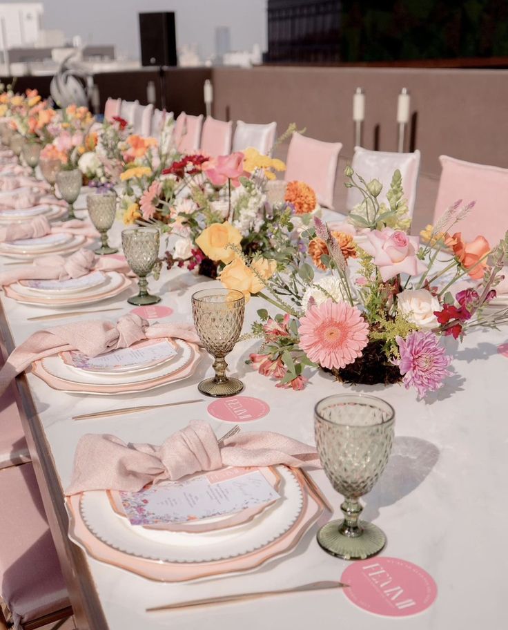 a long table set with place settings and flowers in vases on top of it