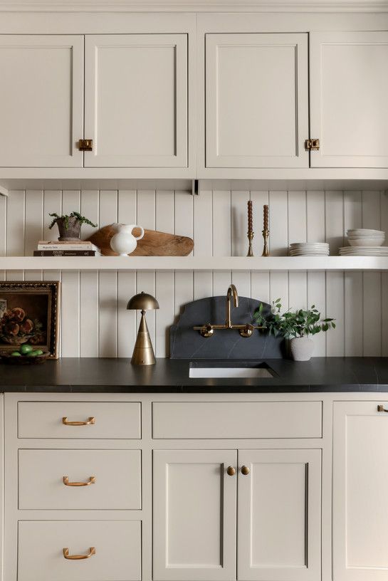 a kitchen with white cupboards and black counter tops, gold pulls on the cabinet doors