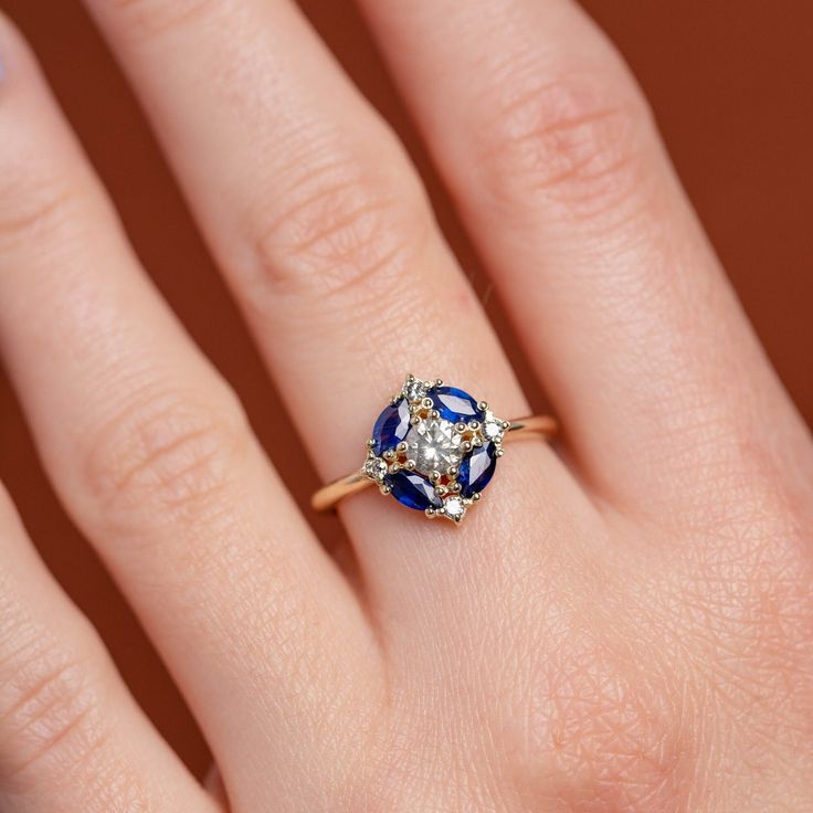 a woman's hand with a blue and white ring on her left hand, showing the center stone