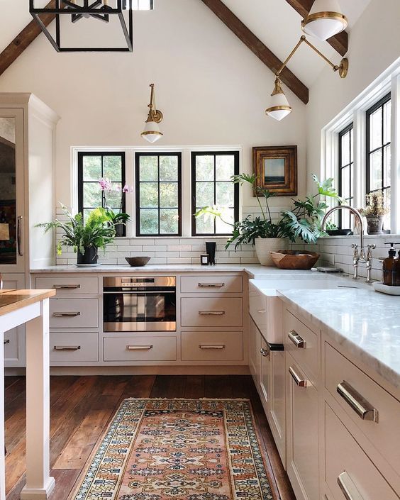 a kitchen with wooden floors and white walls, an area rug on the floor is in front of the stove