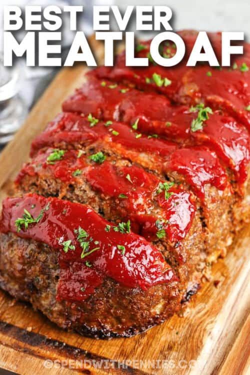 meatloaf on a cutting board with ketchup and green garnish