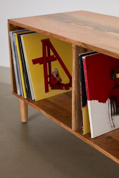 a wooden shelf with books and magazines in it on top of concrete floored area