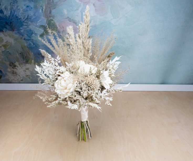 a bouquet of white flowers sitting on top of a wooden floor next to a wall