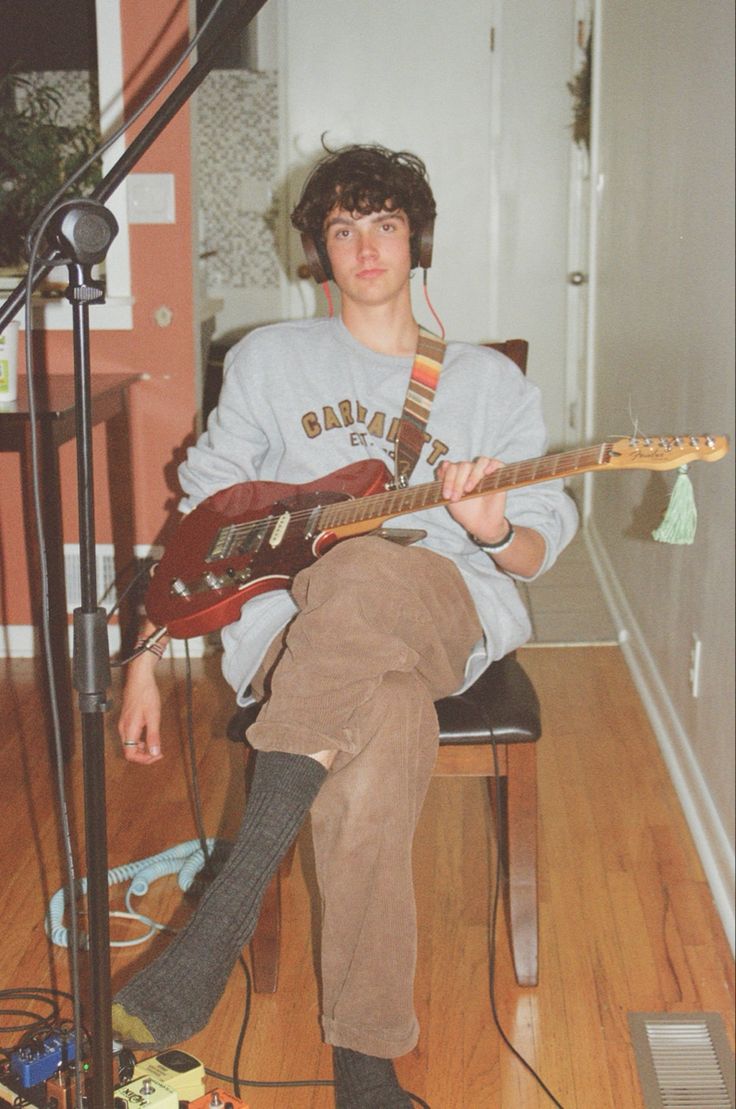 a young man sitting on top of a chair holding a guitar