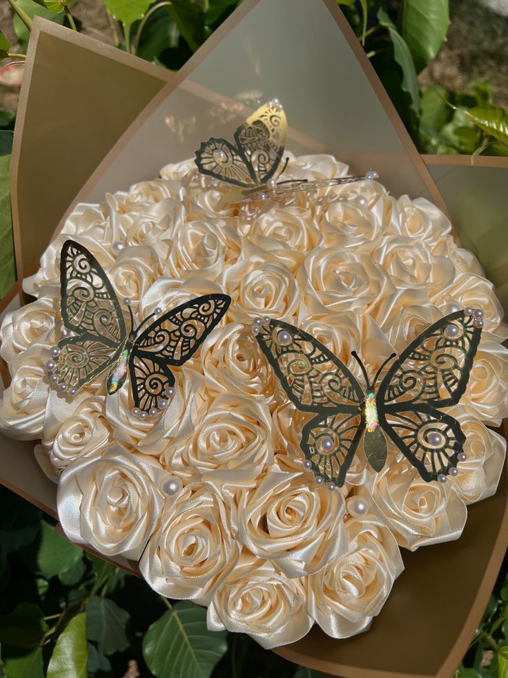 two butterflies sitting on top of a bouquet of roses in the shape of a wreath