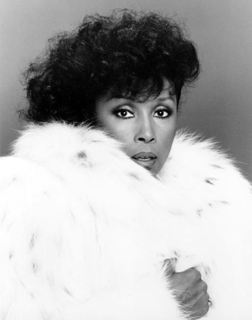 a black and white photo of a woman wearing a fur coat