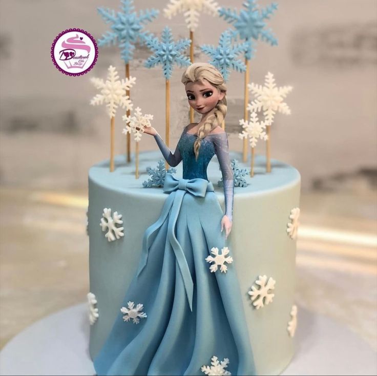 a frozen princess cake with blue frosting and white snowflakes on the top