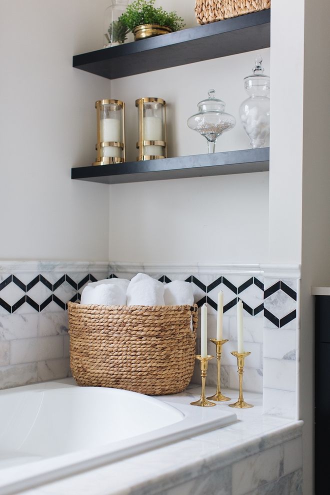 a bathroom with black and white tile, gold accents and open shelving above the bathtub